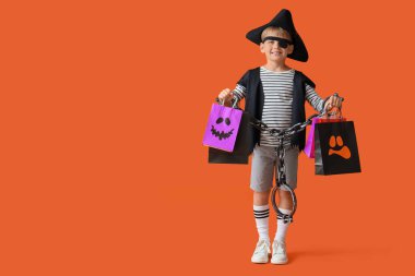Cadılar Bayramı 'nda korsan gibi giyinmiş küçük çocuk. Turuncu arka planda hediye çantaları var.