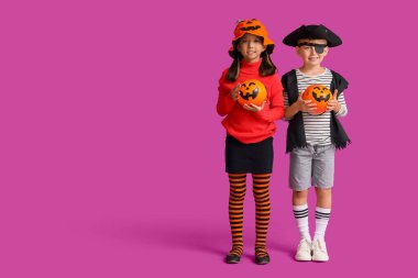 Cadılar Bayramı için giyinmiş küçük çocuklar ve menekşe arkaplanda şekerler.