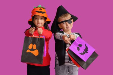 Cadılar Bayramı için giyinmiş küçük çocuklar ve menekşe arka planda hediye çantaları.
