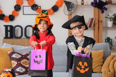 Cadılar Bayramı için giydirilmiş küçük çocuklar ve hediye çantaları.