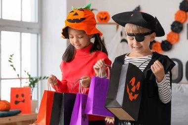 Cadılar Bayramı için giydirilmiş küçük çocuklar ve hediye çantaları.