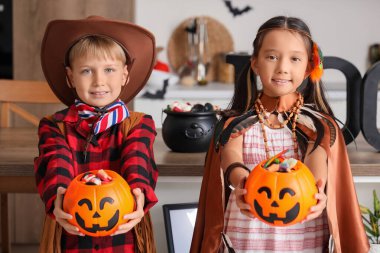 Cadılar Bayramı için giyinmiş küçük çocuklar ve mutfakta şekerler.