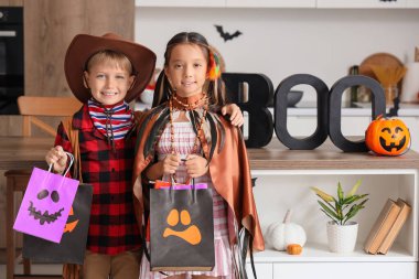 Cadılar Bayramı için giyinmiş küçük çocuklar ve hediye çantaları mutfakta.