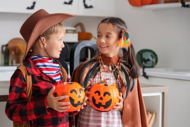 Cadılar Bayramı için giyinmiş küçük çocuklar ve mutfakta şekerler.