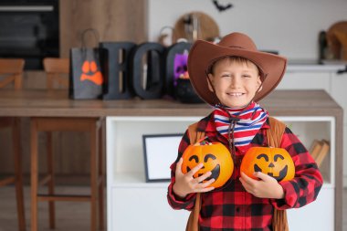 Cadılar Bayramı 'nda kovboy gibi giyinmiş, mutfakta şekerleri olan küçük bir çocuk.