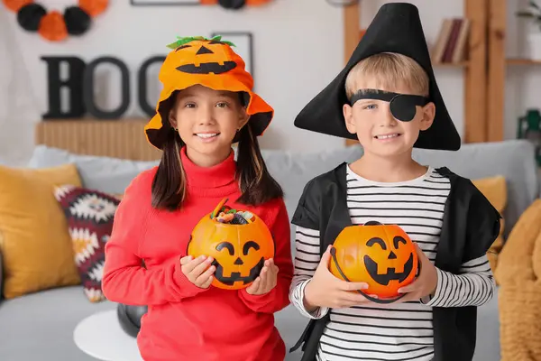 Cadılar Bayramı için giydirilmiş küçük çocuklar ve evde şekerler.