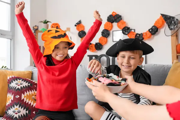 Cadılar Bayramı için giyinmiş küçük çocuklar evde şeker alıyorlar.