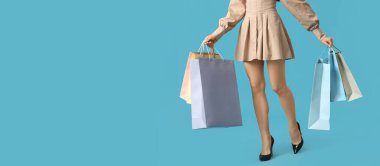 Açık mavi arka planda alışveriş torbaları olan genç bir kadın ve mesaj için yeri var. Kara Cuma indirimi