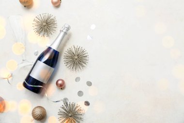 Bir şişe şampanya, cam ve beyaz arka planda Noel süslemeleri.