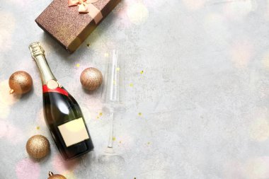 Noel toplarıyla dolu bir şişe şampanya ve grunge grisi arka planda hediye kutusu.