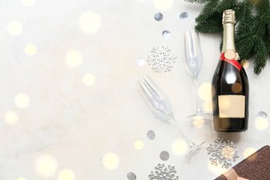 Noel süslemeleri, bardaklar ve köknar dalı olan bir şişe şampanya.