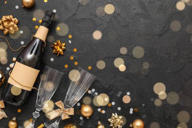 Karanlık arka planda bir şişe şampanya, bardak ve Noel süslemeleri.