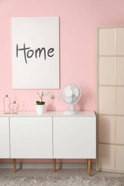 Oturma odasının içinde modern elektrikli vantilatör olan şık bir dolap.