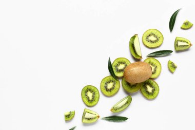 Taze kivi dilimleri ve beyaz arka planda yapraklar.