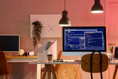 Karanlık ofisin içinde cihazları olan programcının çalışma yeri