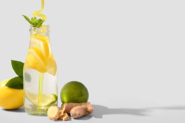 Beyaz arka planda zencefilli ve naneli bir şişe lezzetli limonata.