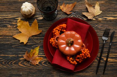 Sonbahar masası kabak şeklinde tencere, böğürtlen ve ahşap masa üzerinde kuru yapraklarla servis edilir.