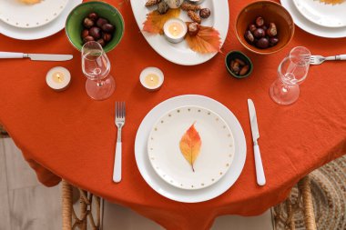 Yanan mumlar ve kuru yapraklarla sonbahar masa ayarı, yakın plan