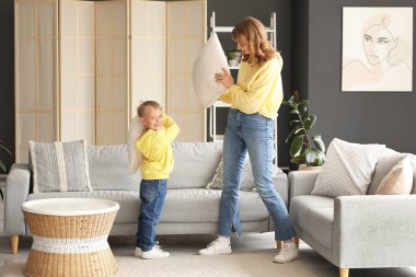 Mutlu anne ve küçük oğlu evdeki oturma odasında yastıklarla savaşıyor.