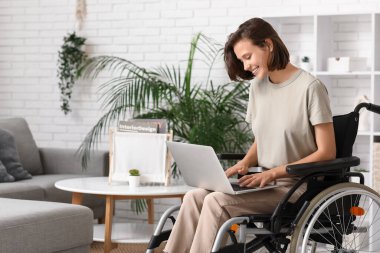 Evinde dizüstü bilgisayarı olan tekerlekli sandalyede güzel bir kadın.