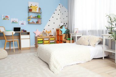 Yatak, çalışma masası ve oyuncakları olan çocuk odasının içinde.