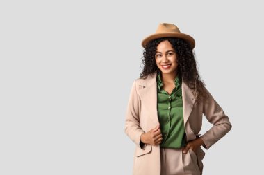 Gri arka planda şık takım elbiseli güzel, mutlu, Afro-Amerikan kadın.