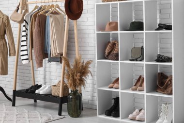 Sonbahar giysileri ve aksesuarlarıyla modern giyinme odasının içinde.