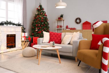 Oturma odasının içinde Noel ağacı, kanepe ve şömine var.