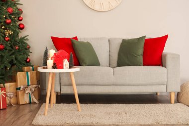 Oturma odasının içinde Noel ağacı, kanepe ve mum tutacağı var.