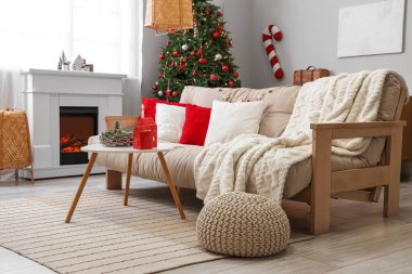 Beyaz kanepesi, sehpası, Noel ağacı ve şöminesi olan festival salonu.