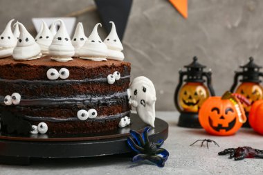 Tatlı Cadılar Bayramı pastası. Gri arka planda kremalı hayaletler, jöle örümcekler ve fenerlerle süslenmiş.