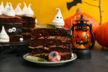 Siyah masada sarı arka planda hayalet, göz ve jelibon solucanları olan lezzetli bir Cadılar Bayramı pastası.