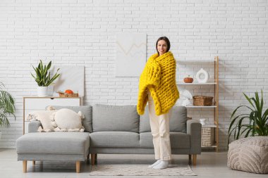 Oturma odasında tuğla duvarlı, ılık sarı ekoseli güzel bir kadın.