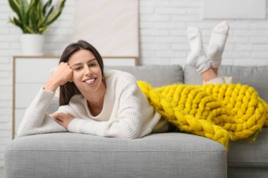 Oturma odasındaki kanepede sıcak sarı ekoseli güzel bir kadın yatıyor.