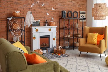 Cadılar Bayramı için dekore edilmiş oturma odasının içinde şömine, kanepe ve koltuk var.