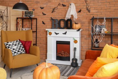 Cadılar Bayramı için dekore edilmiş oturma odasının içinde şömine, kanepe ve koltuk var.