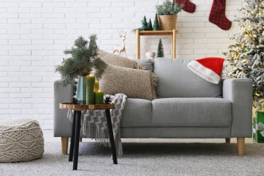 Gri kanepe, Noel ağacı ve kahve masasında yanan mumlarla dolu bir oturma odası.
