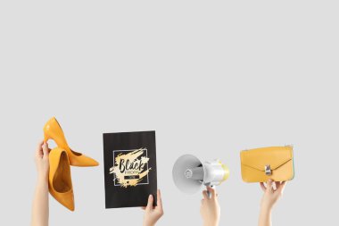 Kartlı kadın elleri, megafon ve arka planda aksesuarlar. Kara Cuma İndirimi