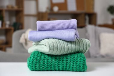 Oturma odasındaki masada şık bir kazak yığını.