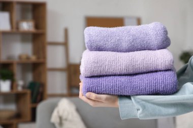 Evde şık kışlık süveter yığını olan kadın elleri, yakın plan.