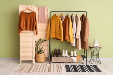 Soyunma odasının iç tarafında şık kalın kıyafetler, ayakkabılar ve katlanan perdeler var.