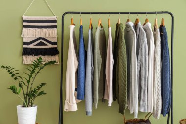 Yeşil duvarın yanında şık ve kalın giysilerle dolu bir oda.