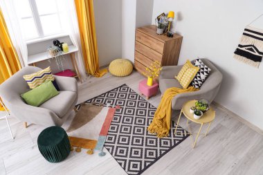 Gri koltukları, masası ve pufları olan şık bir oturma odası.