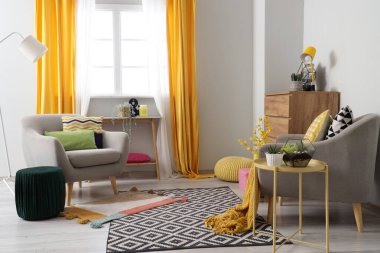 Gri koltukları, masası ve pufları olan şık bir oturma odası.