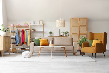 Elbise askısı, kanepesi ve masası olan bir oturma odası.