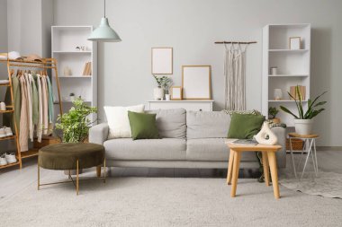 Elbise askısı, kanepe ve raf üniteleriyle oturma odasının içinde.