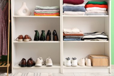 Dolapta katlanmış kıyafetler ve ayakkabılar olan raflar.