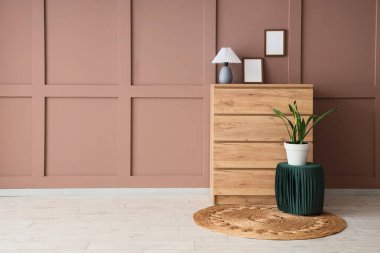 İçinde lamba olan çekmeceler, boş çerçeveler ve odada kahverengi duvarın yanında puf.