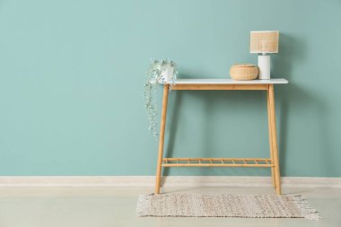 Yeşil duvarın yanındaki sepetli ve çiçekli şık lamba.