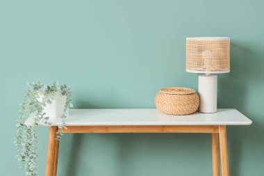 Yeşil duvarın yanındaki sepetli ve çiçekli lamba.